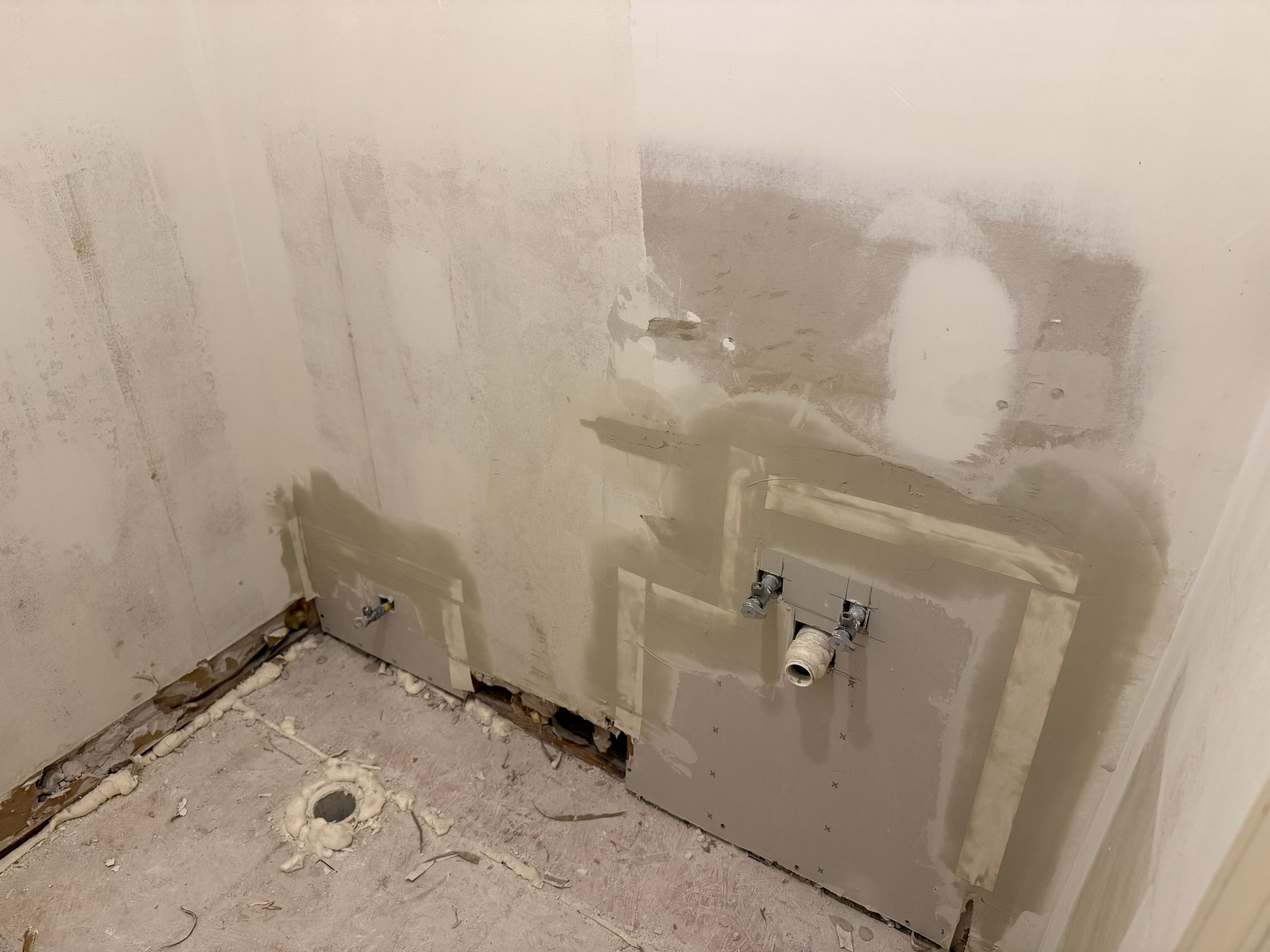 Raw drywall patch work on plumbing wall before finish coat