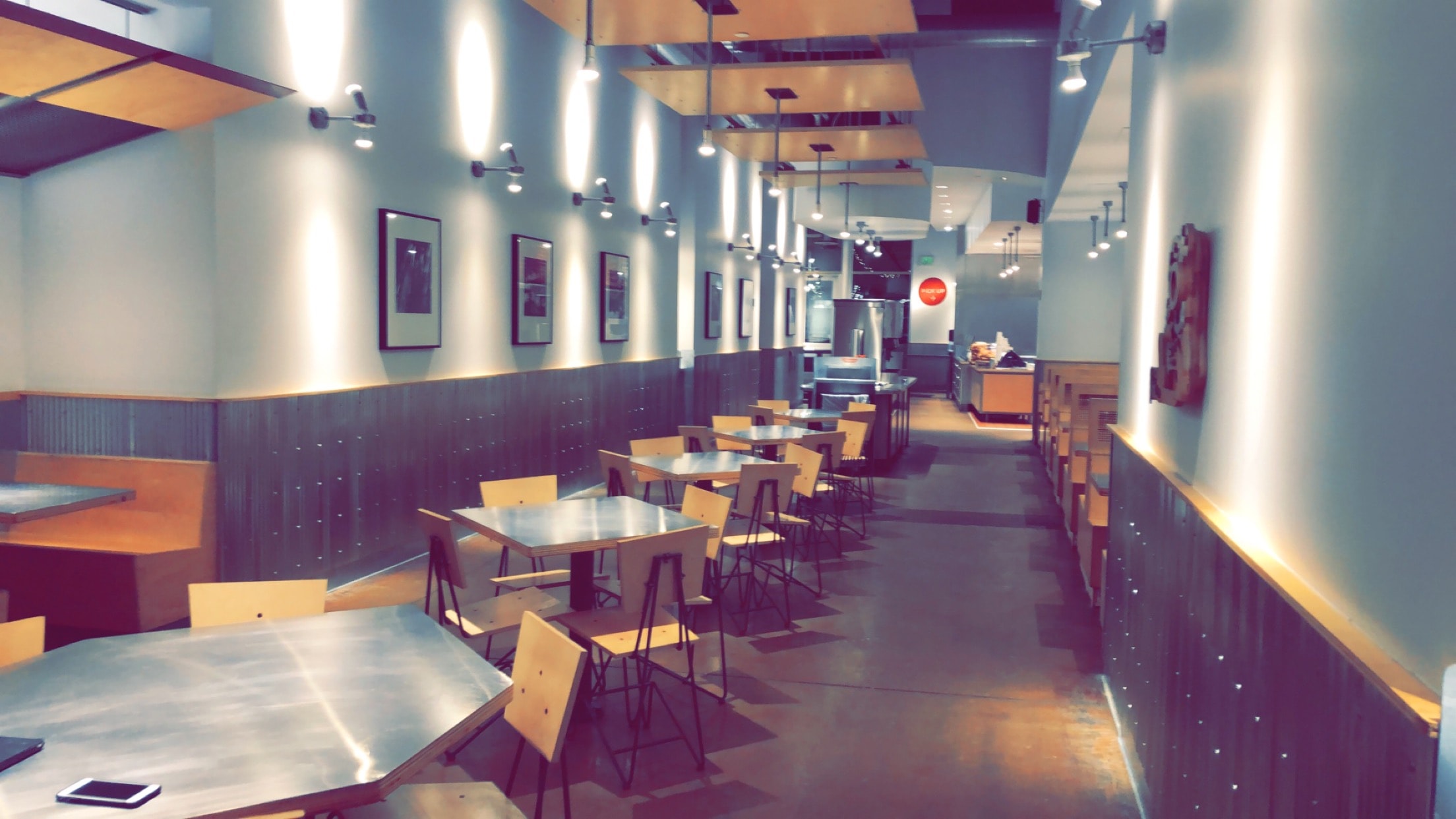 Chipotle renovation — completed dining room with corrugated tin wainscoting, painted walls, and wood ceiling panels — St. Paul, MN